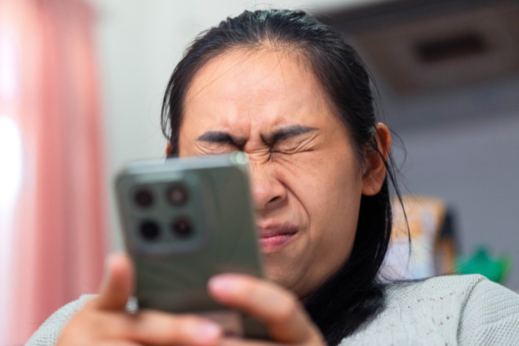 Woman holding phone squeezing her eyes