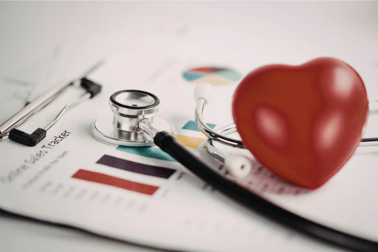 stethoscope and a small red plastic heart on top of a research paper