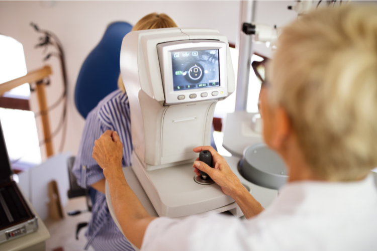 Optometrist performing eye exam using autorefractor machine to assess patient’s vision in eye care clinic