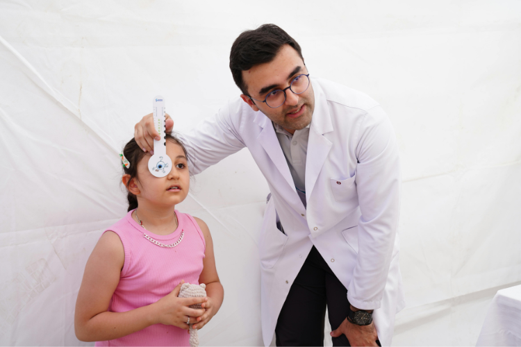 Optometrist performing eye exam on child using eye chart tool in modern vision care clinic