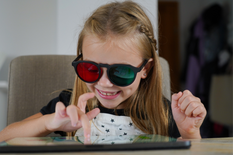 Child using AmblyoPlay vision therapy on a tablet with specialized red-green glasses, improving visual skills through screen-based exercises