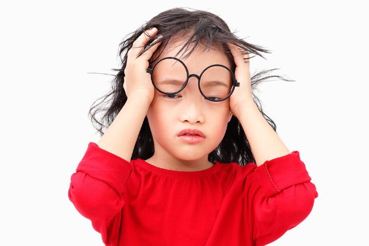 Child wearing oversized glasses holding head, showing symptoms of digital eye strain from screen time