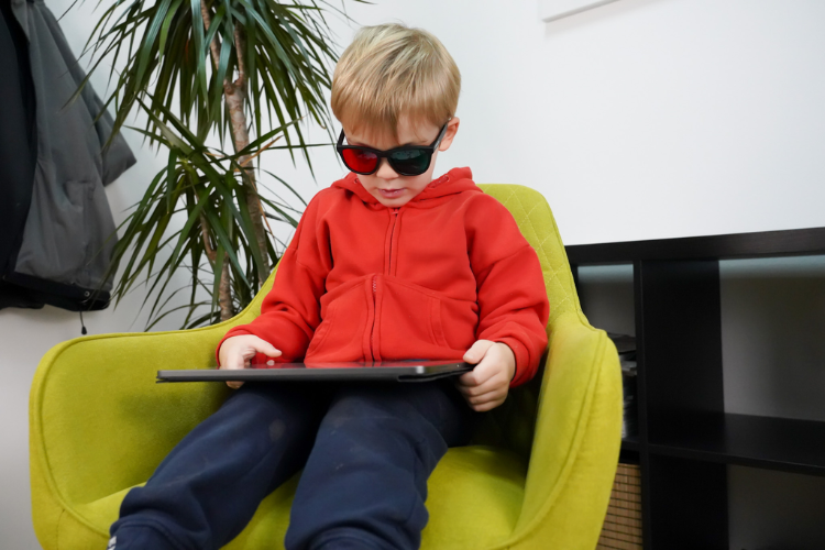 Child wearing specialized red-green glasses while completing daily AmblyoPlay vision therapy training